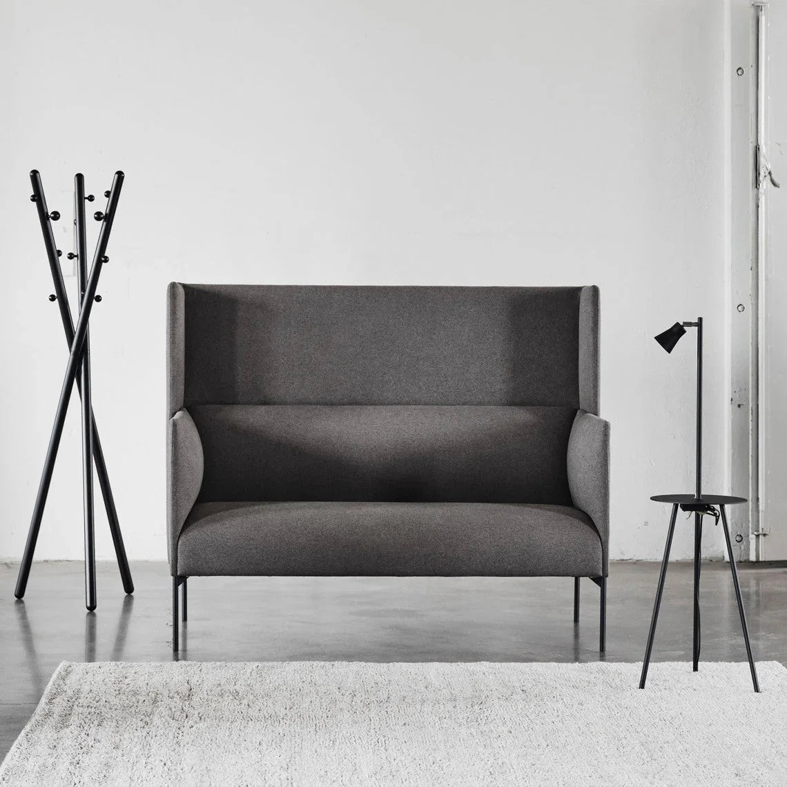 Modern gray fabric sofa with black metal legs, styled with minimalist coat rack and floor lamp in Singapore home