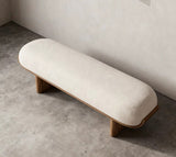 A modern upholstered bench with a rounded cream fabric cushion and natural wood legs