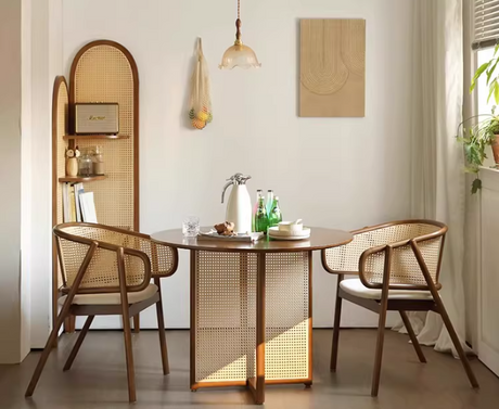 Dining room with a round wooden table and wicker chairs, featuring a mirror and decorative items.
