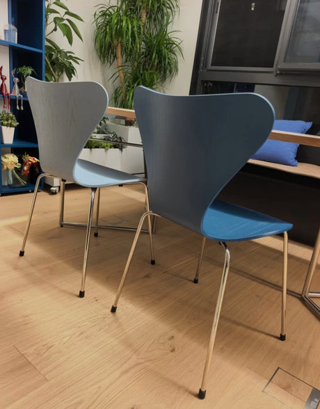 Modern blue and gray chairs with chrome legs in a bright, plant-filled room