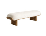 A modern low bench with a thick, rounded off-white bouclé upholstered seat and a curved medium-brown wooden frame and legs, shown on a plain white background.