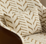 A close-up of a textured throw pillow and matching upholstered chair in an off-white bouclé fabric with a tan geometric chevron pattern.